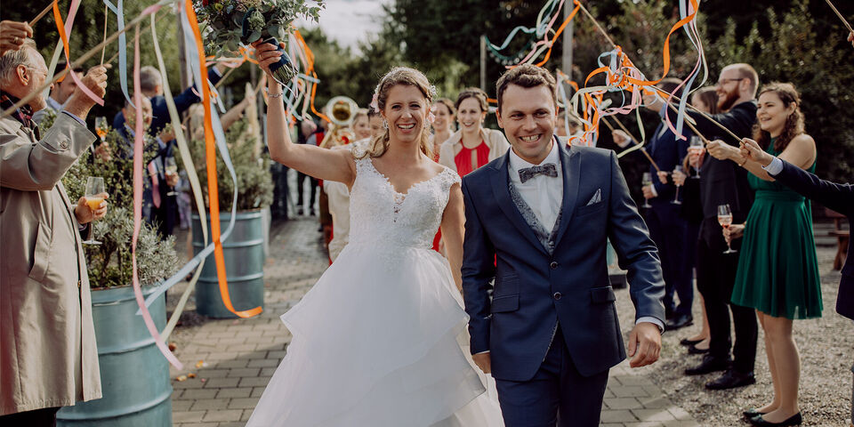 Das glückliche Brautpaar tanzt mit bunten Bändern und Freude bei ihrer Hochzeit.