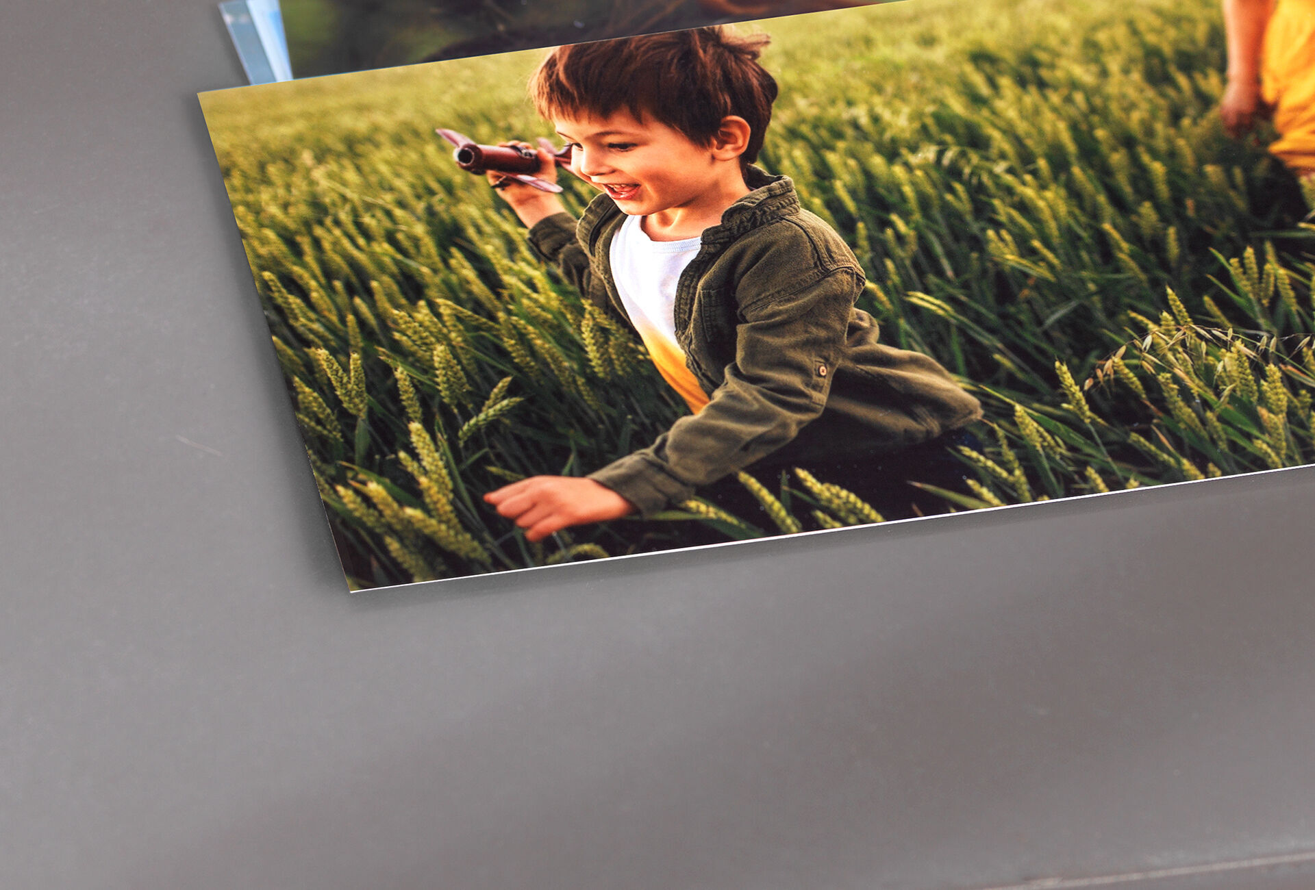 Ein Kind mit Spielzeug auf einem Feld voller grünem Gras.
