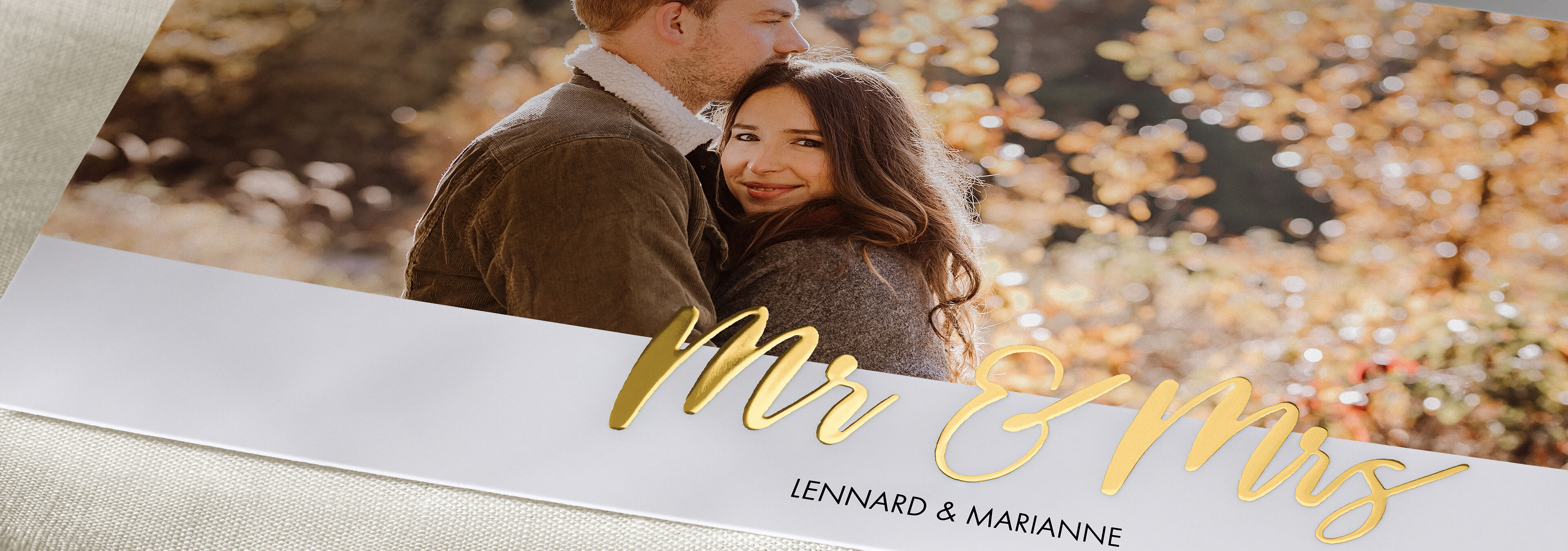Ein glückliches Paar sitzt in der Natur, umgeben von herbstlichen Farben. Der Schriftzug "Mr & Mrs" ist elegant auf dem Bild.