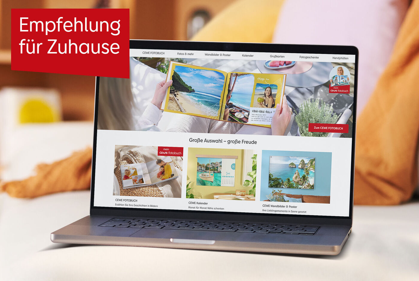 Laptop mit geöffneter CEWE Fotowelt Startseite steht auf einem Sofa, oben links rotes Schild mit Empfehlung für Zuhause