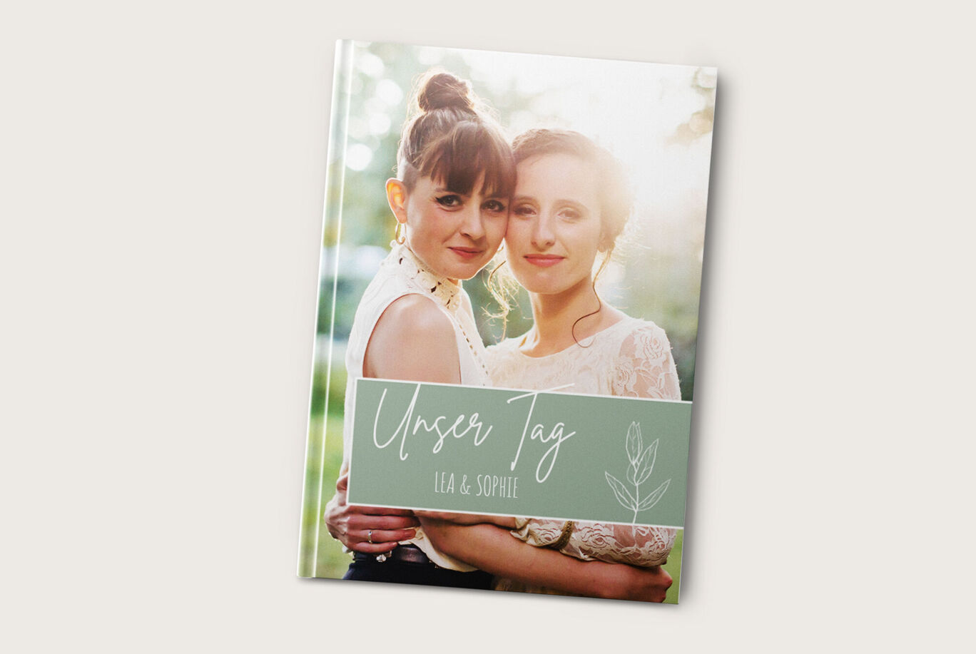 Zwei lächelnde Frauen stehen im Freien, umgeben von Natur, und halten gemeinsam ein Fotobuch in den Händen.