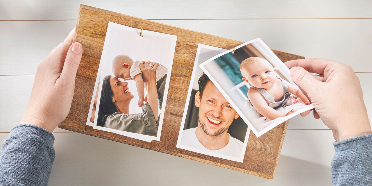 Eine Person hält eine Holzplatte mit Fotos in der Hand. Die Fotos zeigen glückliche Erinnerungen mit Familie und Freunden.