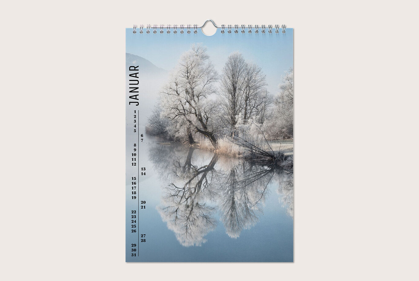 Ein stilvoller Wandkalender für den Monat Januar mit einer frostigen Landschaft. Der Kalender zeigt einen klaren Himmel über einem stillen, spiegelnden See und verschneiten Bäumen.