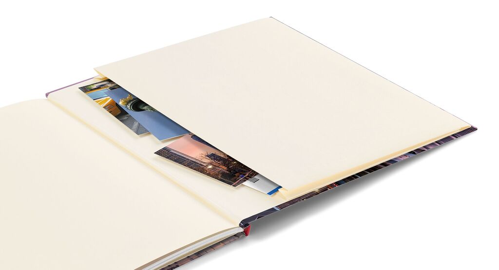 Ein offenes Fotobuch mit leeren Seiten und eingelegten Fotos.