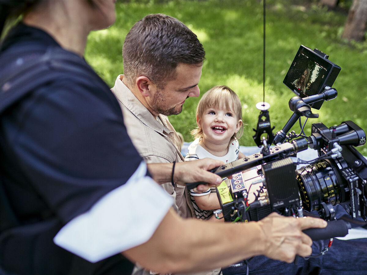 Ein Filmteam filmt im Freien einen Mann mit einem Kind.