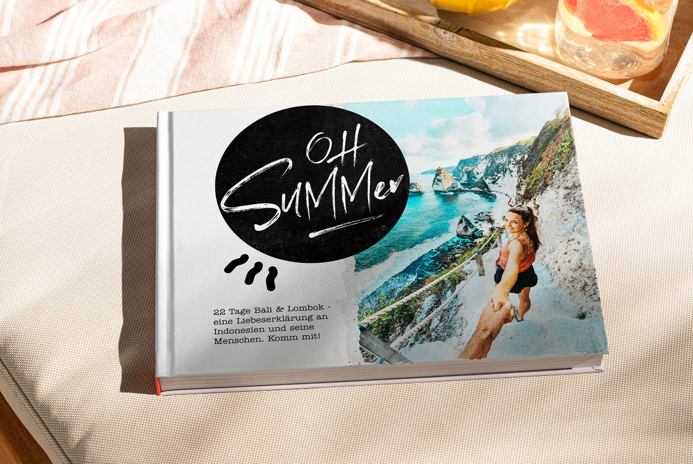 Ein CEWE Fotobuch mit dem Titel "OH SUMMER" und einem b Dieser Bild zeigt eine Frau, die die Aussicht von einer Klippe genießt. Sie strahlt Freude aus und symbolisiert unvergessliche Sommererinnerungen.