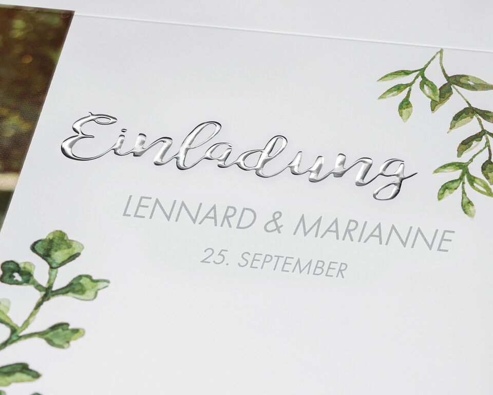 Einladungskarte mit den Namen Lennard und Marianne sowie dem Datum 25. September, umrahmt von grünen Blättern