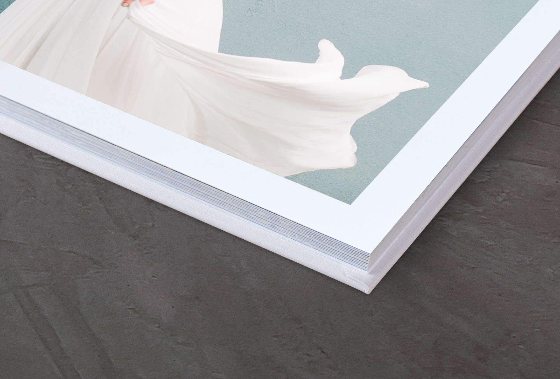 Detailaufnahme eines CEWE FOTOBUCHS mit einem eleganten weißen Cover und einem zarten Hintergrund