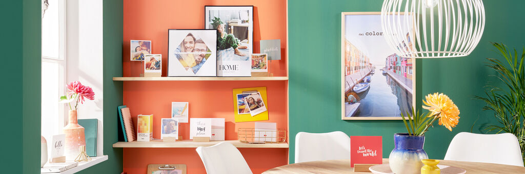 Bunte Wanddekoration mit Fotobüchern, Bildern und Grußkarten auf Regalen.
