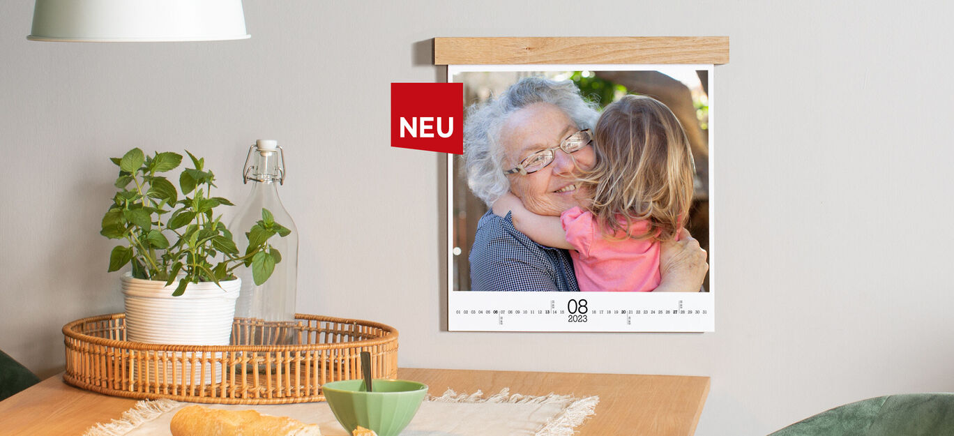 Ein Wandbild zeigt einen Erwachsenen, der ein Kind umarmt. Das Bild ist an der Wand befestigt und ein Tisch mit Pflanzen ist im Vordergrund.