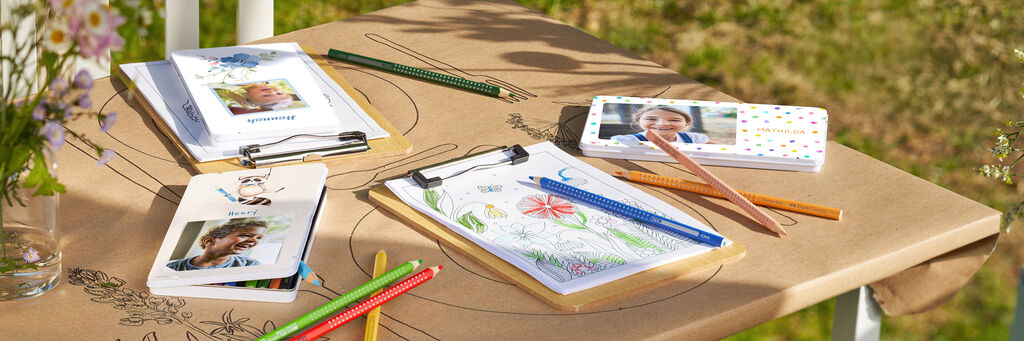 Arbeitsplatz mit Malutensilien, Skizzen und CEWE Fotobuch.