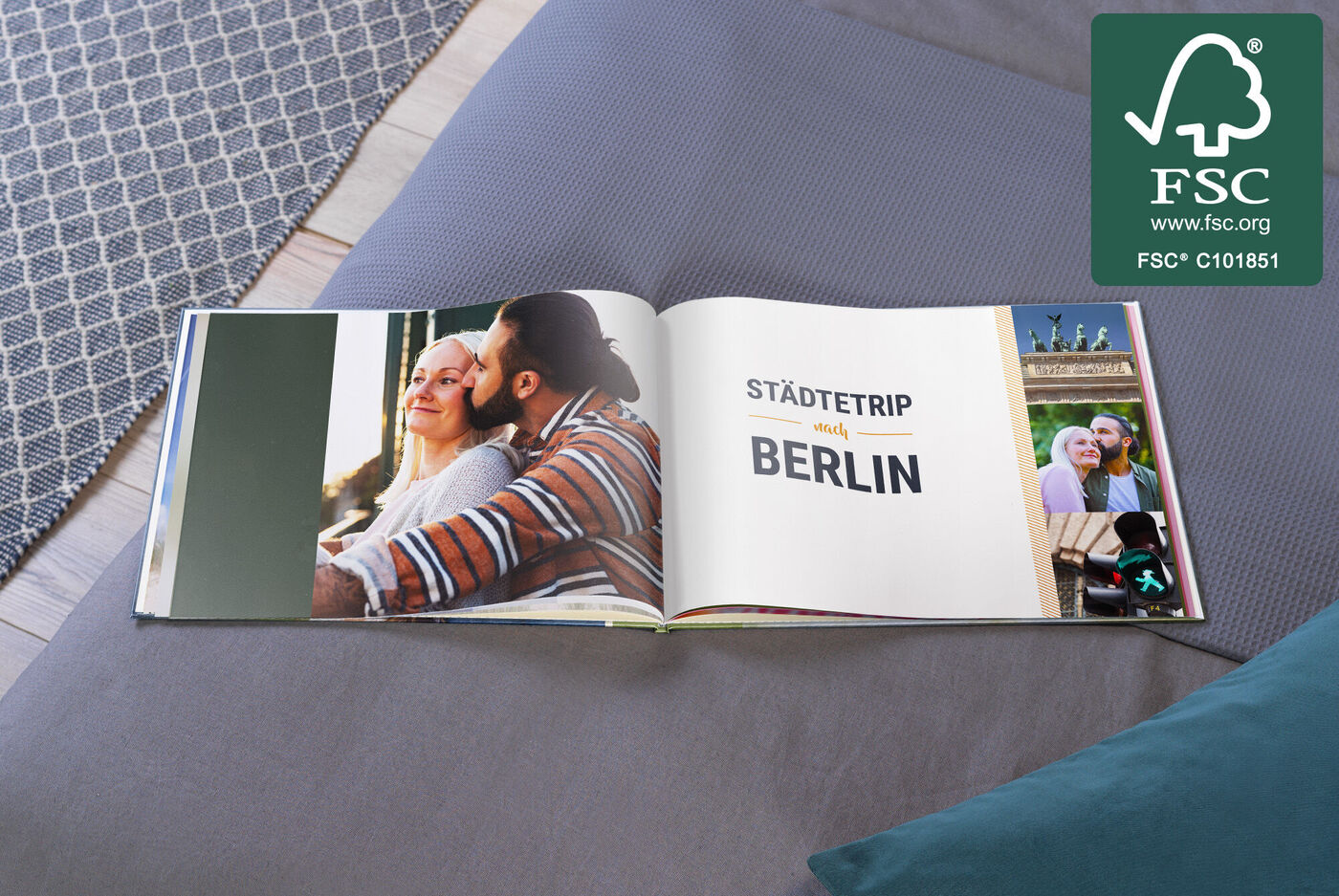 Ein geöffnetes Fotobuch zeigt Erinnerungen an einen Städetrip nach Berlin, auf einer Couch platziert, mit hübschem Design.