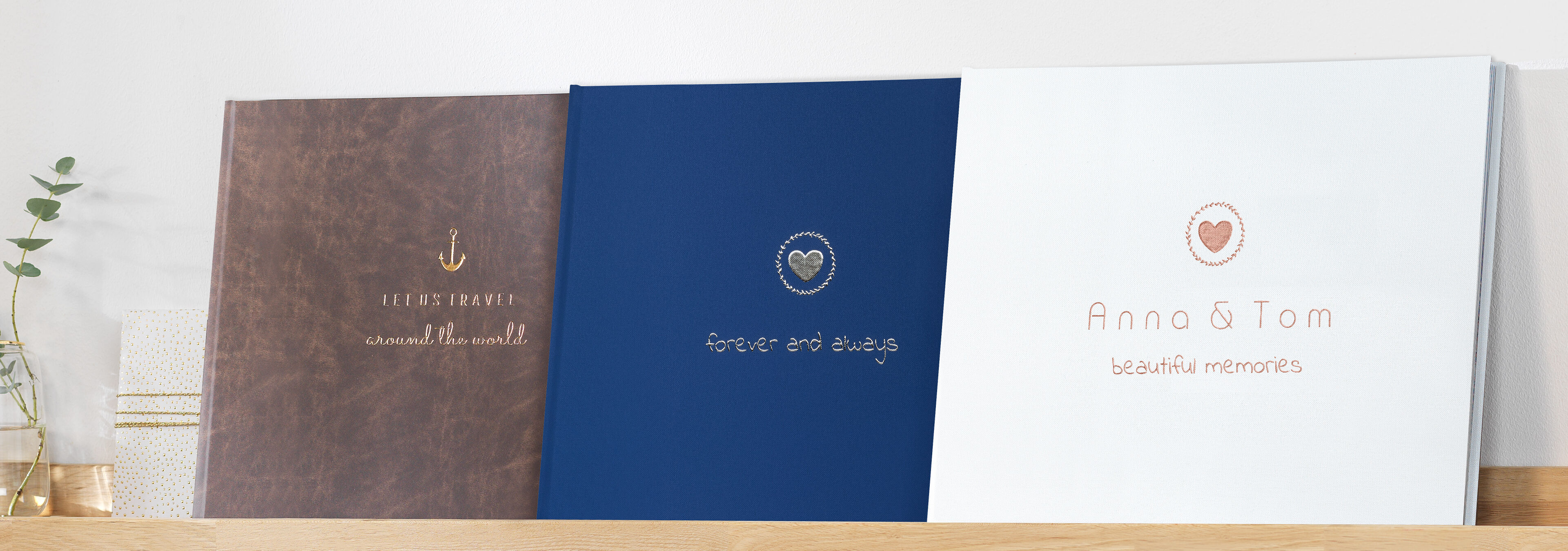 Drei kreative Fotobücher auf einem Regal, jedes mit einzigartigem Design und Titel