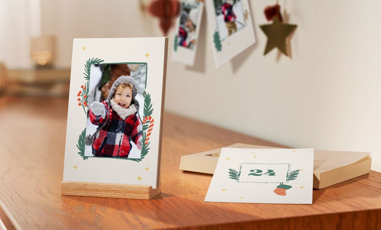 Ein dekorativer Tisch mit einem Bilderrahmen und Grußkarten. Der Rahmen zeigt eine festliche Gestaltung mit Weihnachtsmotiven. Die besinnliche Atmosphäre lädt zum Schenken von Erinnerungen ein.