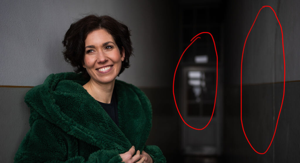 Frau in grünem Mantel steht in einem Flur.