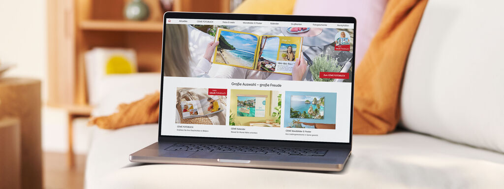 Laptop steht auf einer Couch und zeigt die Startseite der CEWE Fotowelt