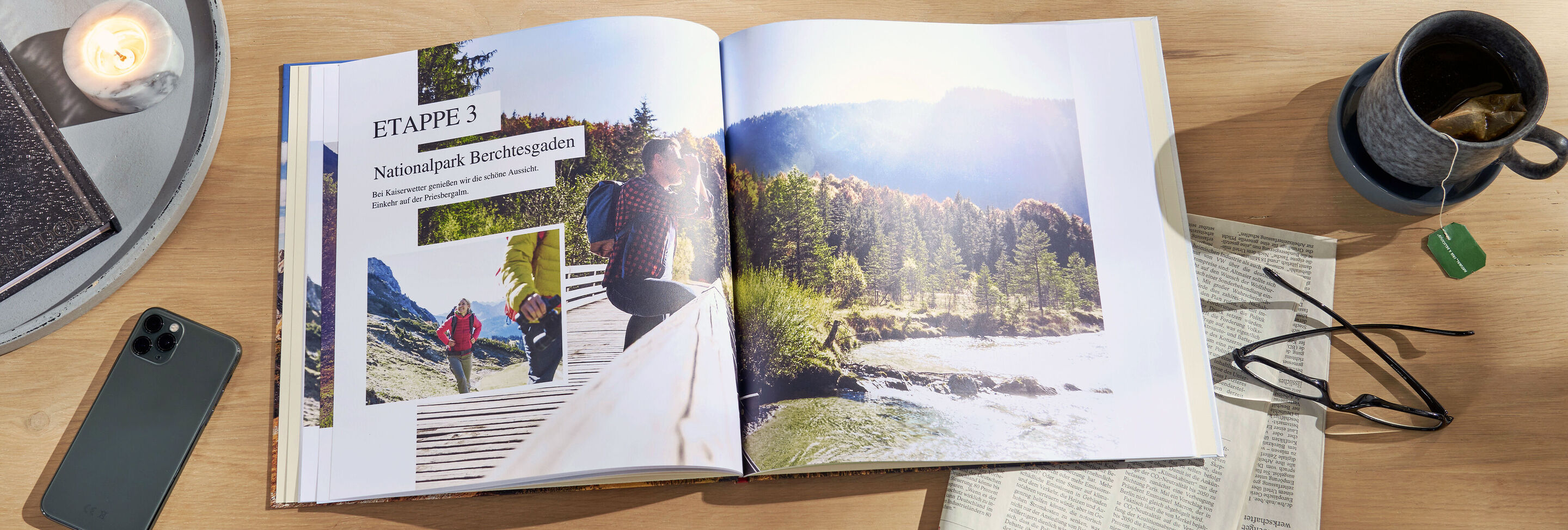 Ein aufgeklapptes CEWE FOTOBUCH mit Fotos von Reiseerinnerungen in einer Naturlandschaft.