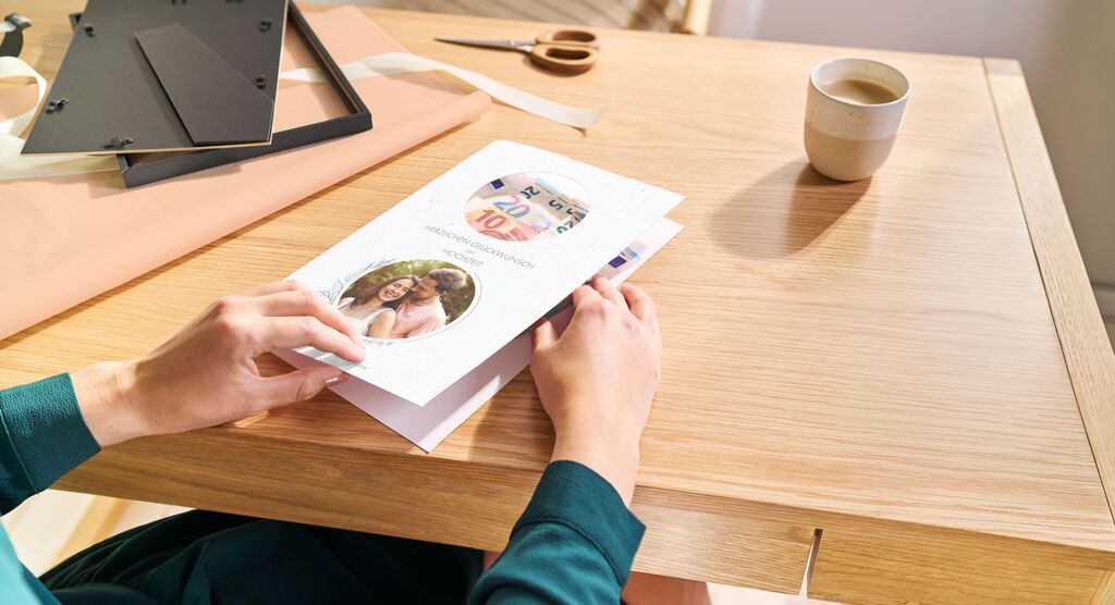 Eine Person blättert durch ein CEWE Fotobuch auf einem Tisch.