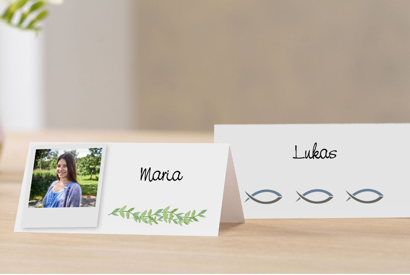 CEWE Grußkarten als Tischkarten mit den Namen Maria und Lukas, Fischsymbolen und einem Porträt