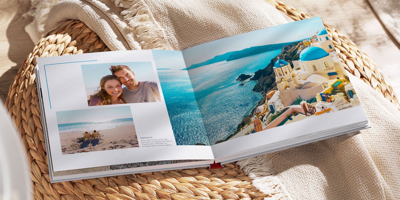 Aufgeschlagenes CEWE FOTOBUCH mit Urlaubsfotos von einer Küstenlandschaft.