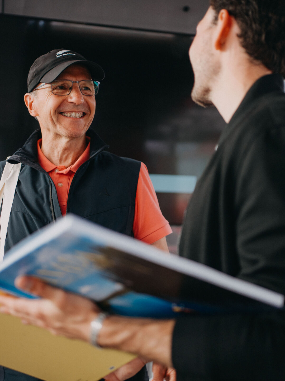 Zwei Männer diskutieren über ein aufgeschlagenes Fotobuch. Sie lachen.