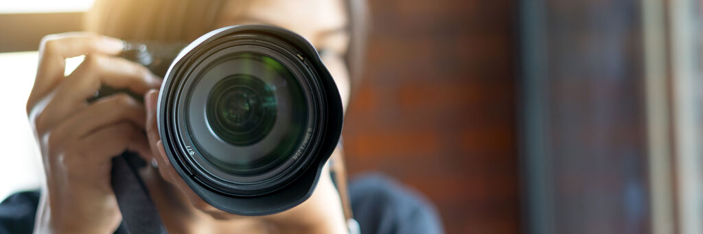 Eine Frau hält eine Kamera und blickt durch den Sucher