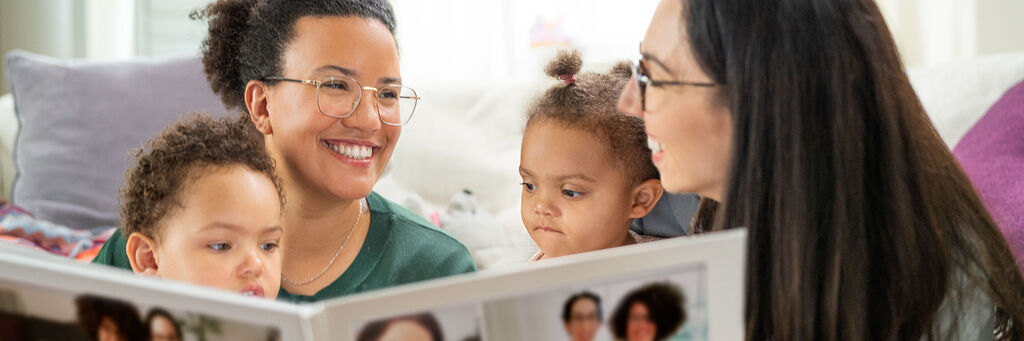 Eine Familie sieht sich gemeinsam ein CEWE Fotobuch an und teilt Freude und Erinnerungen.