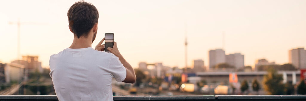 Person fotografiert in der Abendsonne die Berliner Skyline mit dem Handy