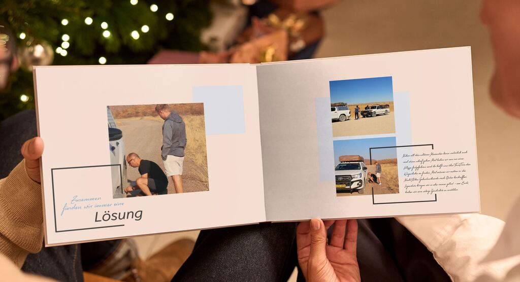 Zwei Personen blättern in einem Fotobuch mit Erinnerungen bei festlicher Beleuchtung.