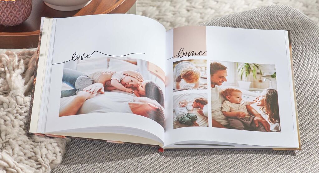 Ein offenes Fotobuch auf einem Tisch mit Bildern von glücklichen Familienmomenten und dem Schriftzug "love" und "home"