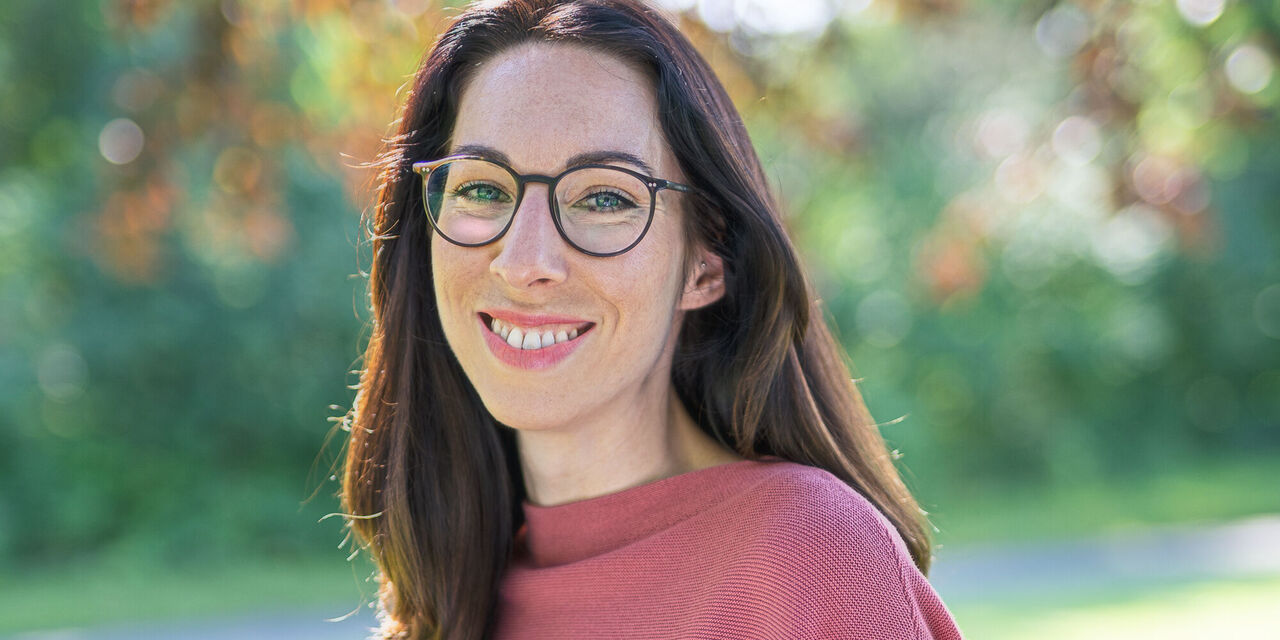 Frau in einem roten Pullover im Freien, umgeben von Bäumen