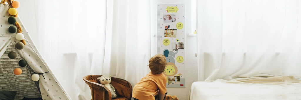 Ein Kind betrachtet eine Wand mit vielen Bildern und Notizen in einem hellen, freundlichen Raum