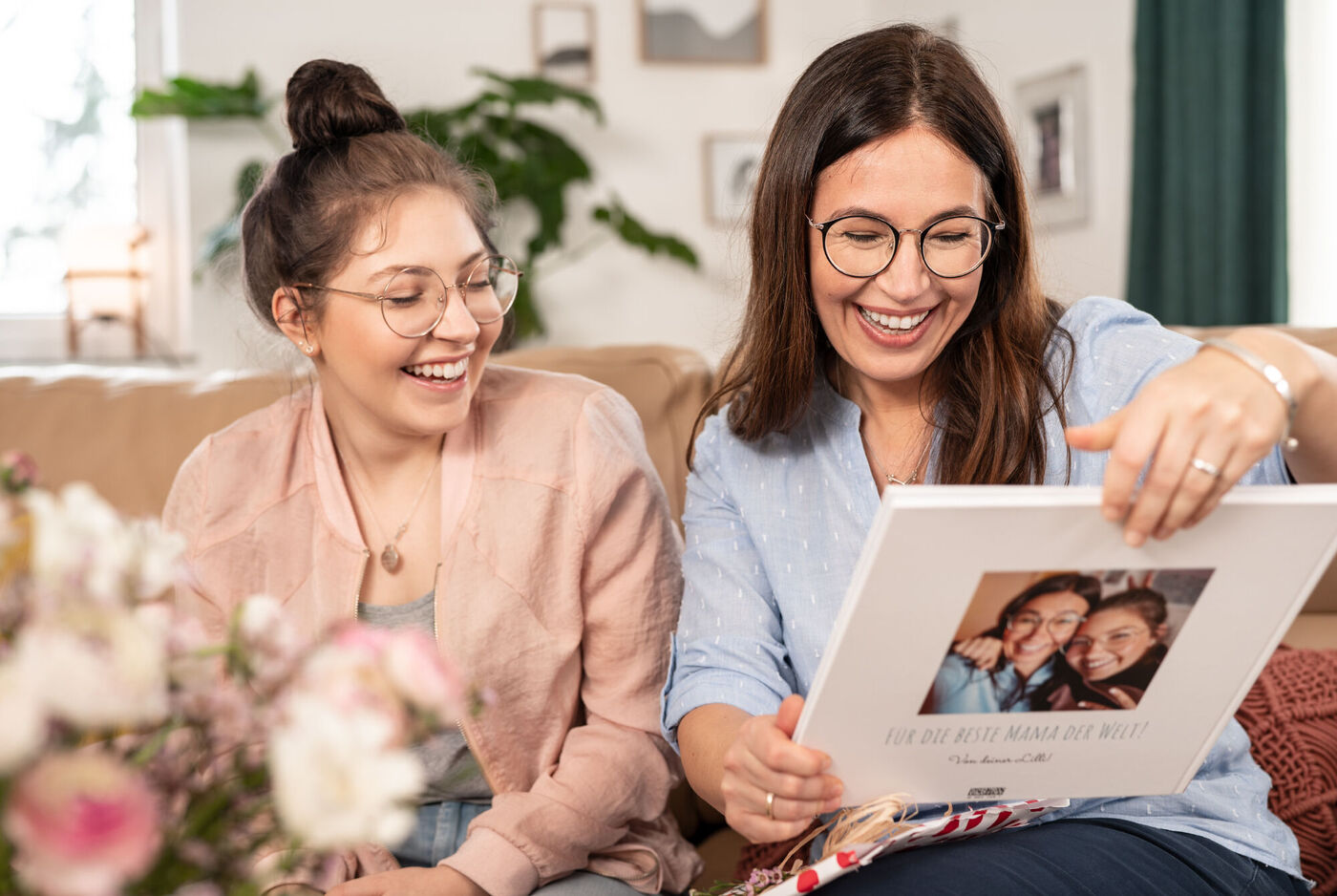 Zwei Personen schauen sich ein Fotobuch an und lächeln. Das Fotobuch zeigt schöne Erinnerungen und gefällt ihnen sehr.