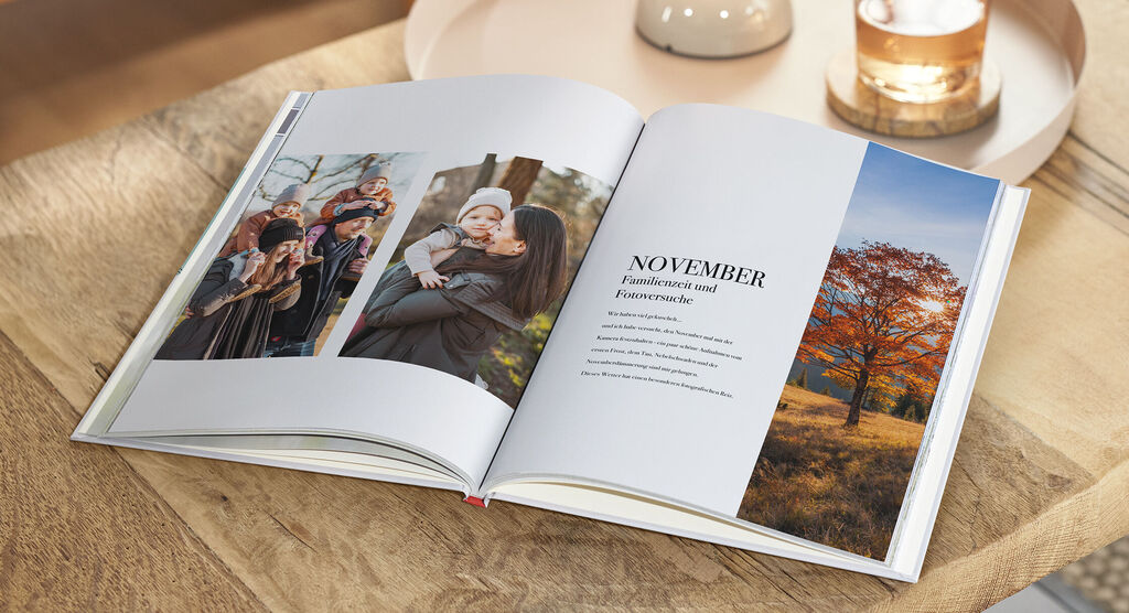 Offenes CEWE FOTOBUCH mit Fotos von einer Familie im Herbstpark und einem Baum mit buntem Laub