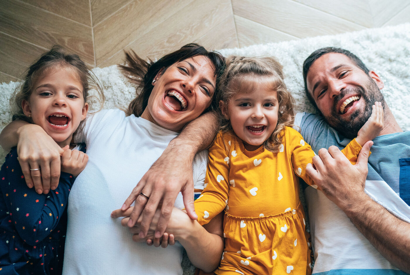 Familie liegt glücklich auf dem Boden und hält sich an den Händen