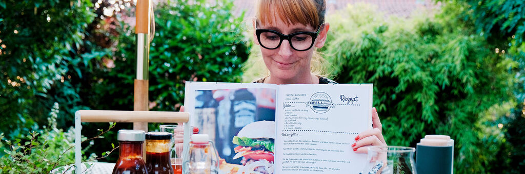 Eine Person hält eine Speisekarte in einem Restaurant mit grüner Umgebung