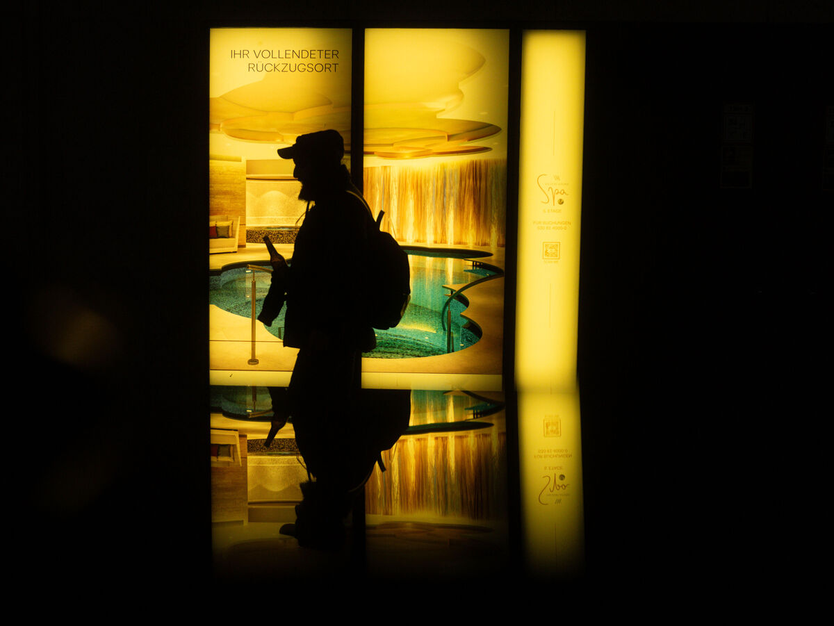 Dunkle Silhouette einer Person vor warm gelb leuchtenden Fenstern mit Spiegelung auf dem Boden