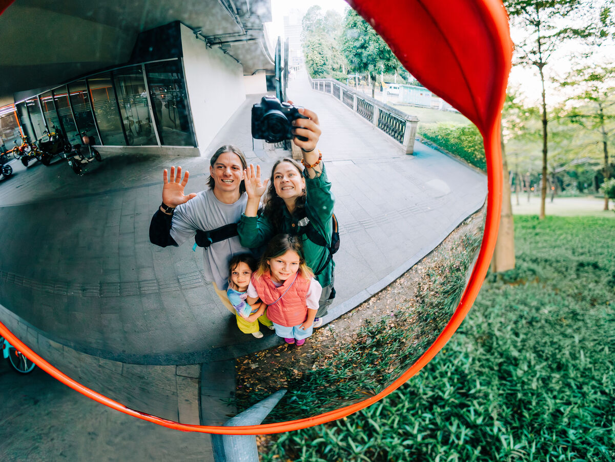 Familie macht Selfie in einem Verkehrsspiegel im Hintergrund die Umgebung zu sehen.