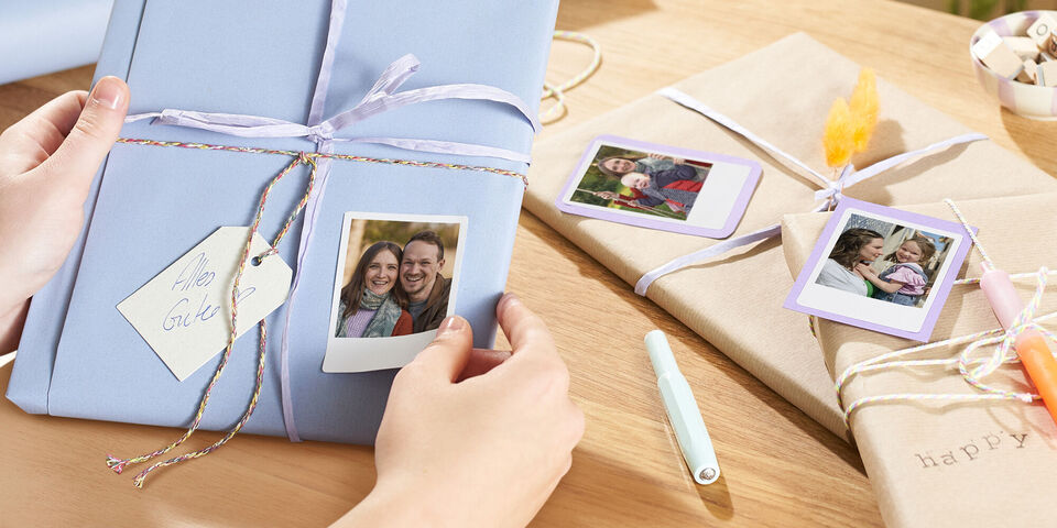 Zwei liebevoll verpackte Geschenke mit Fotos und Etiketten liegen auf einem Tisch