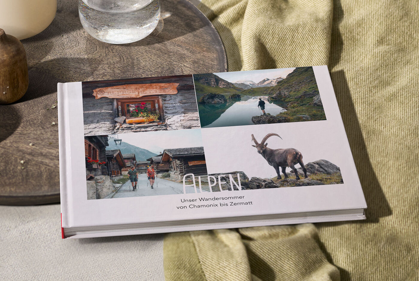 Ein CEWE FOTOBUCH mit Alpenbildern auf einem Tisch, das die Schönheit der Natur zeigt