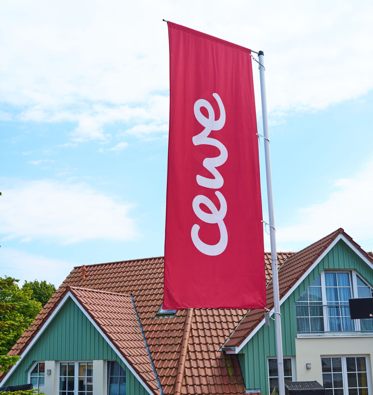 Vor einem Haus weht eine rote Fahne mit dem CEWE Logo.