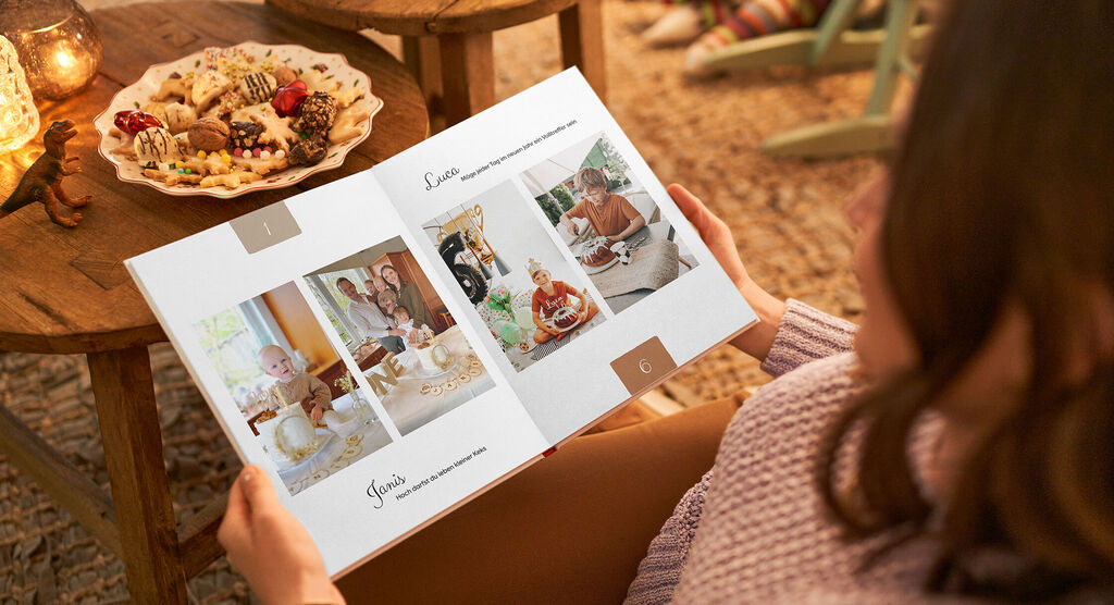 Eine Person blättert durch ein CEWE Fotobuch, das Erinnerungen an festliche Momente zeigt.