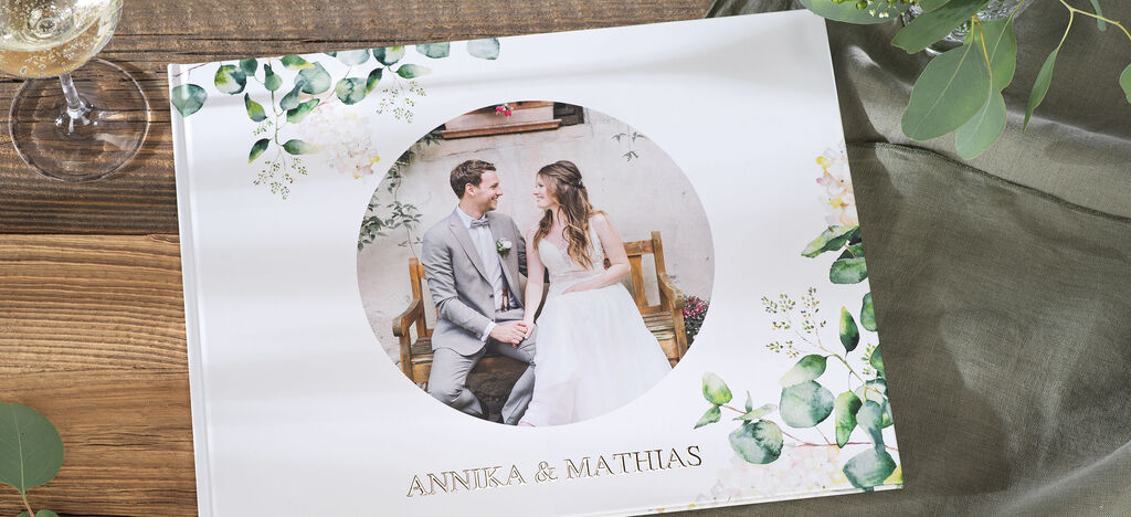 Ein fröhliches Brautpaar in einem eleganten Fotobuch mit floralen Motiven.
