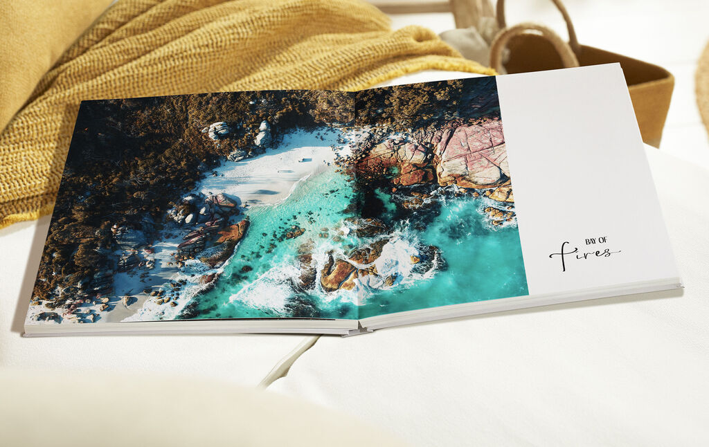 Ein offenes Fotobuch mit wunderschönen Strandszenen auf der linken Seite und einem weißen Bereich auf der rechten Seite