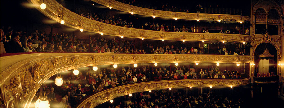 Voller Theatersaal mit verschiedenen Zuschauern und elegantem Interieur