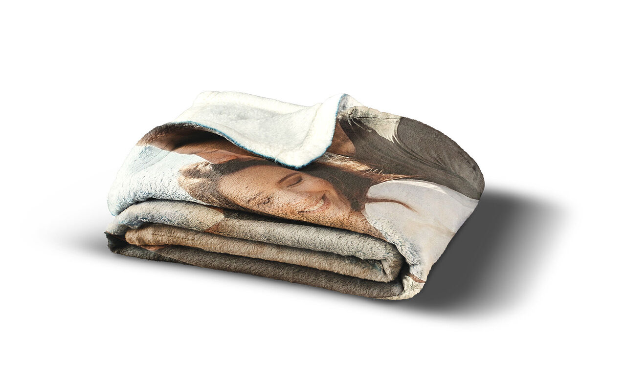 Eine liebevoll gestaltete, gefaltete Decke mit einem fröhlichen Gesicht. Die Decke zeigt ein schönes, persönliches Fotosujet, das Wärme und Gemütlichkeit ausstrahlt.