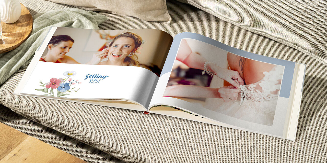Ein geöffnetes CEWE FOTOBUCH auf einer Couch mit Hochzeitsbildern.