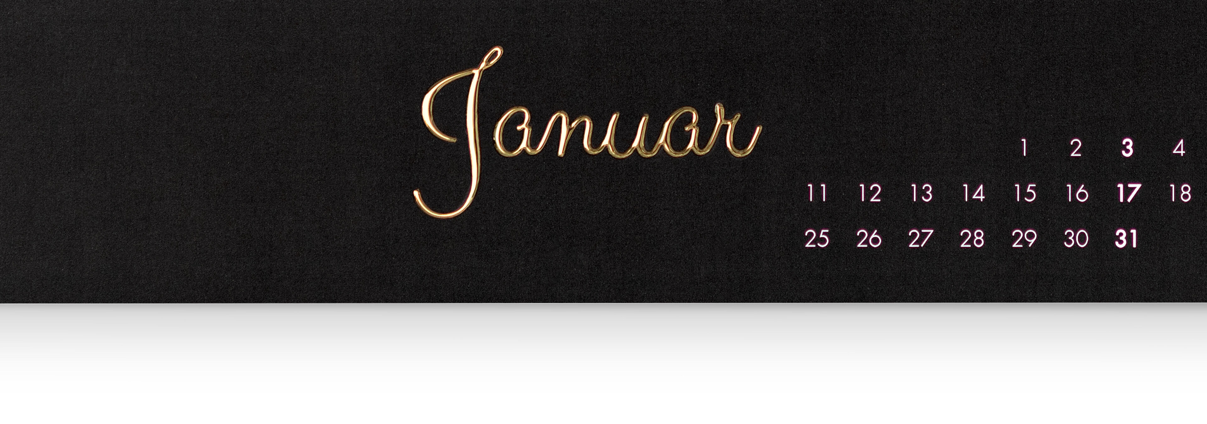 Der Kalender zeigt den Monat Januar mit einer eleganten Schrift in Gold auf schwarzem Hintergrund und kleinen Datenangaben in Rosa.