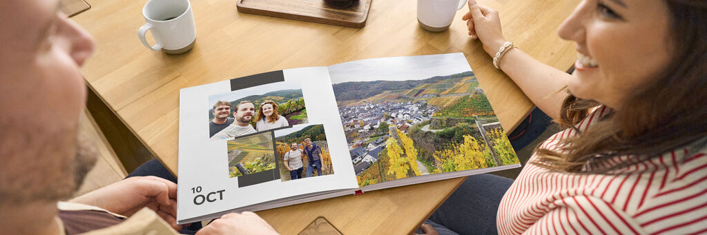 Pärchen betrachtet ein CEWE Fotobuch mit Urlaubserinnerungen.