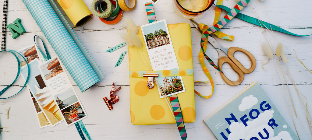 Fröhliche Geschenkverpackung mit buntem Geschenkpapier und Deko, umgeben von kreativen Materialien